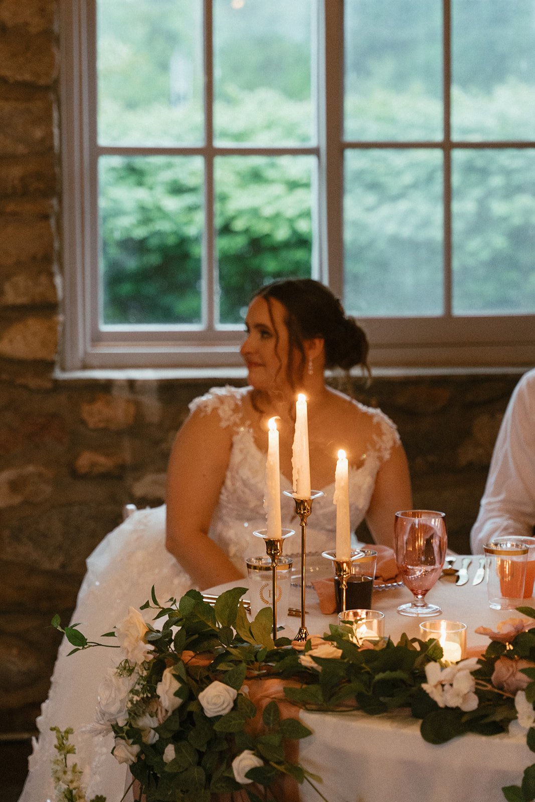 Bride at the reception with taper candles glowing in the foreground