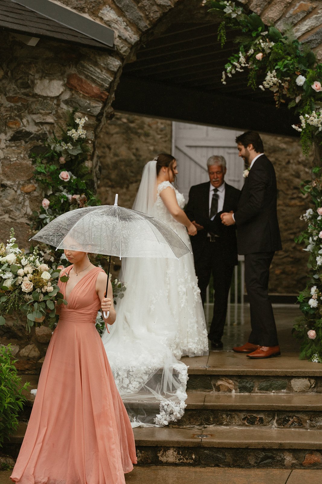 Bride walking up stone stairs with veil flowing behind her