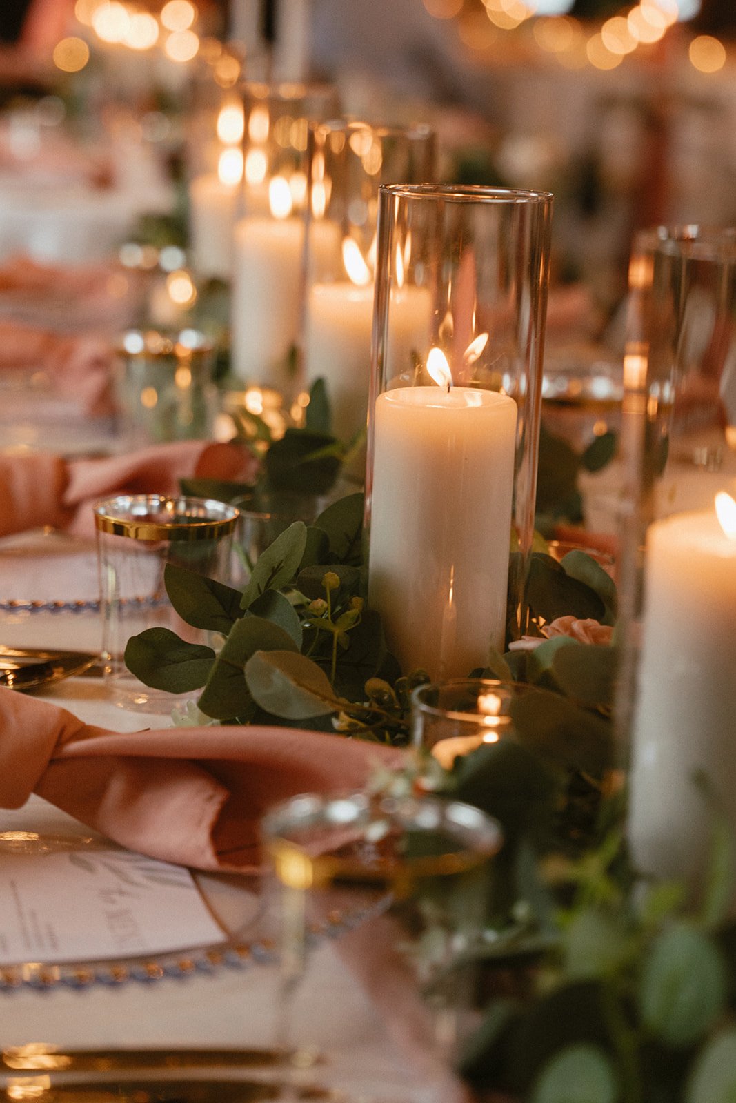 Banquet table lit by tapered candles and greenery