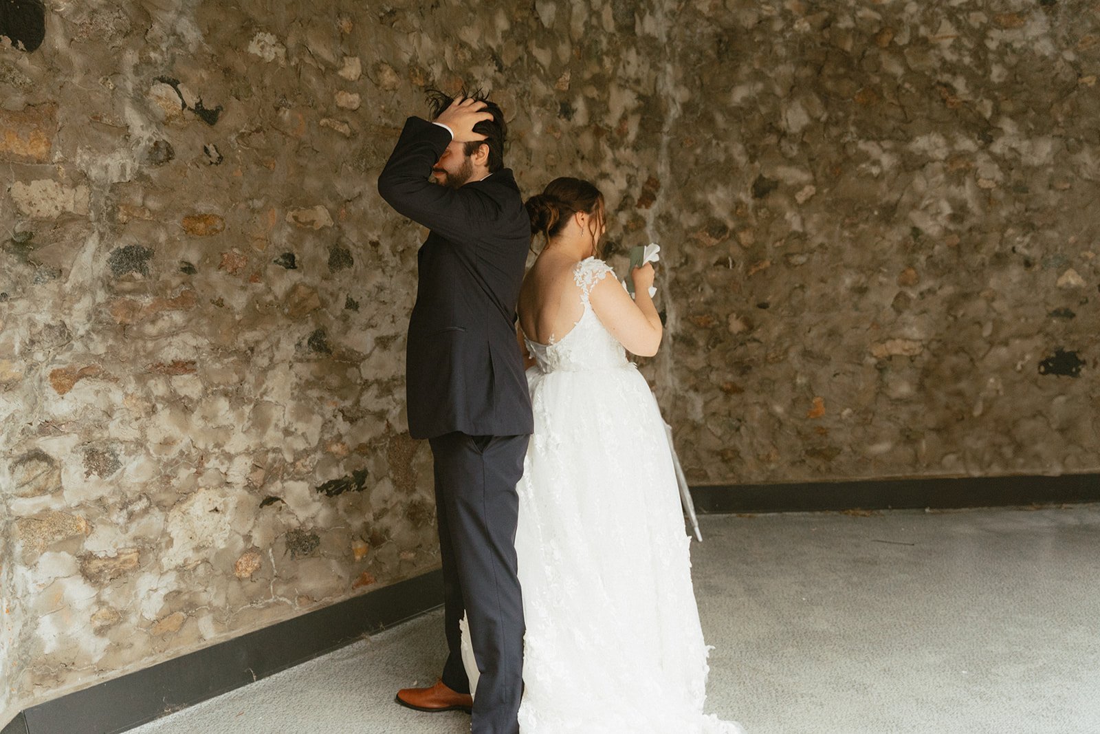 Bride and groom sharing a kiss against a weathered stone wall
