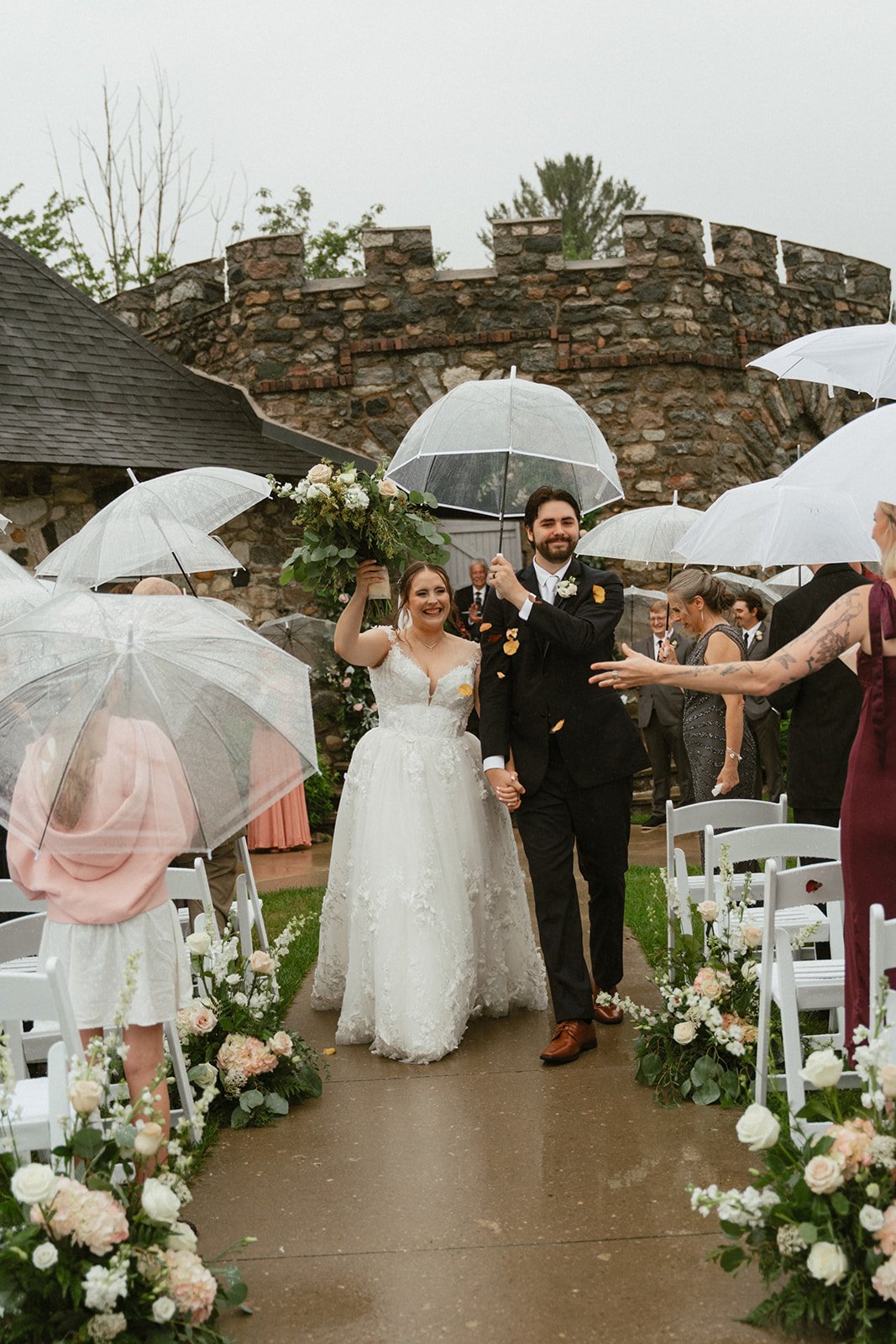 Bride and groom under a clear umbrella after the ceremony