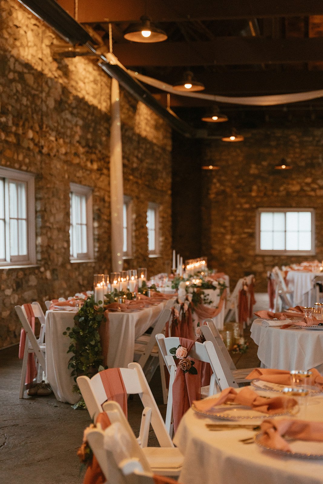 Long banquet table set with florals and candles under warm wooden ceiling beams
