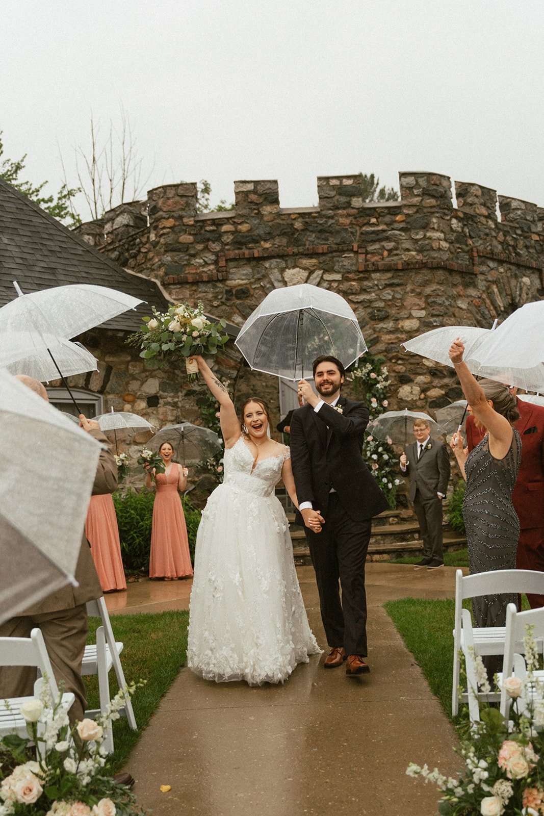 Bride and groom walking down the aisle through clear umbrellas on a rainy day